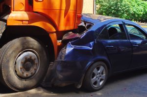 Truck collision involving a damaged blue sedan